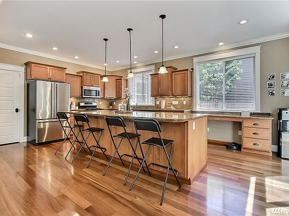 Shot of kitchen from family room, HUGE island, gorgeous flooring, large windows and patio door on your right opening to your backyard and patio. Note large planning desk straight ahead. Included SS appliances and walk-in pantry. 
