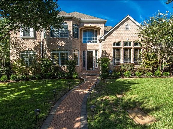 A beautiful brick path leads up to the grand entry way, all surrounded by luscious landscaping.