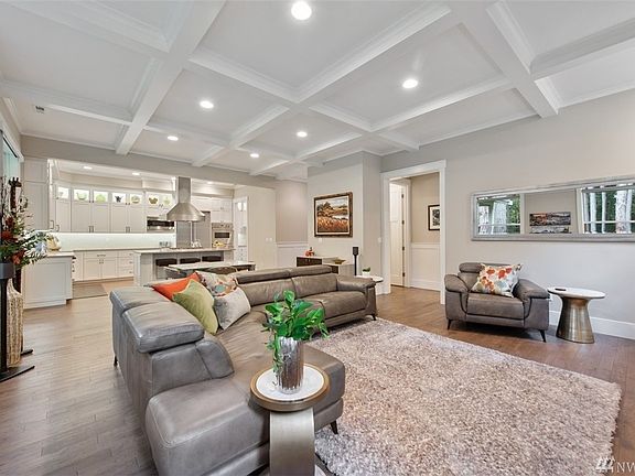 This view of the great room looking into the kitchen shows the hall which leads to the main floor powder bath, mud room and 3 car garage.