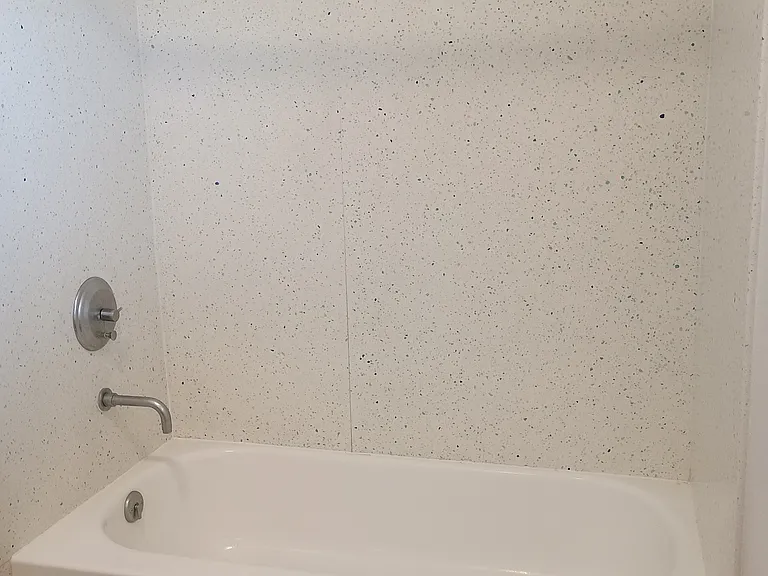 Resurfaced bathrub with modern fixtures. Solid surface tub surround.