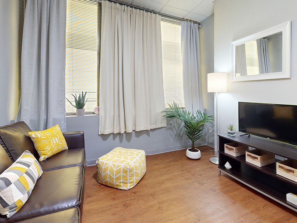 Living Room with Wood-Style Flooring and Curtains at University Plaza NIU Apartments