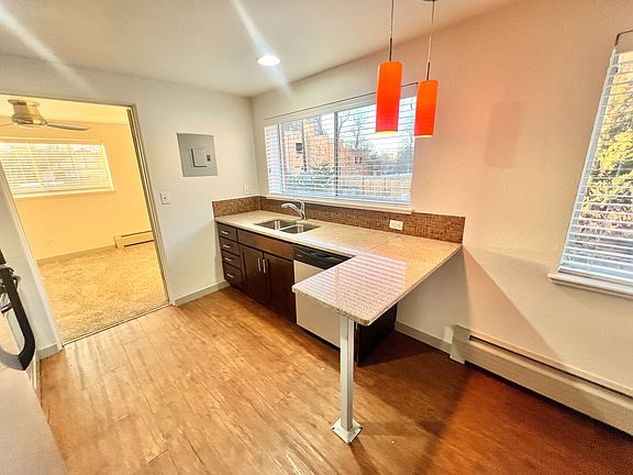 Charming kitchen with sleek countertops, modern lighting, and a cozy adjacent room filled with natural light.