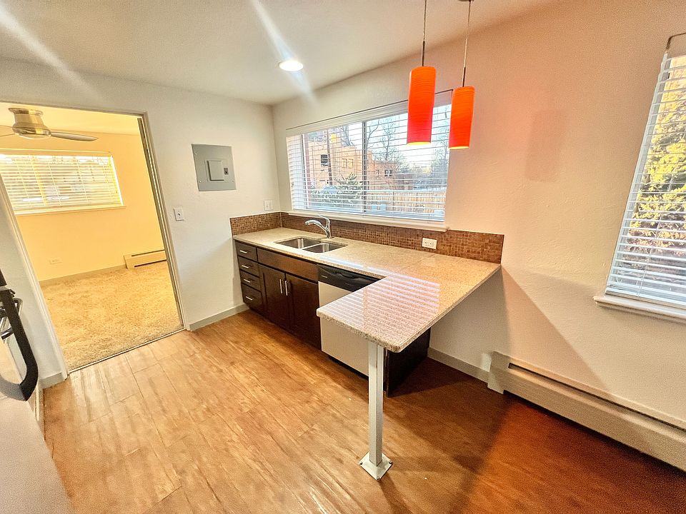 Charming kitchen with sleek countertops, modern lighting, and a cozy adjacent room filled with natural light.