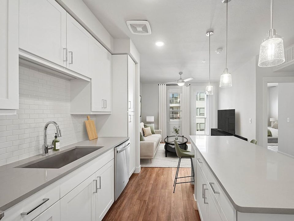 Finish Package II kitchen with stainless steel appliances, white cabinetry, white tile backsplash, grey quartz countertops, and hard surface flooring