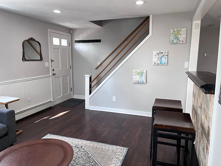 Welcoming entry area with hardwood floors, staircase access, and convenient wall hooks plus breakfast-bar seating.