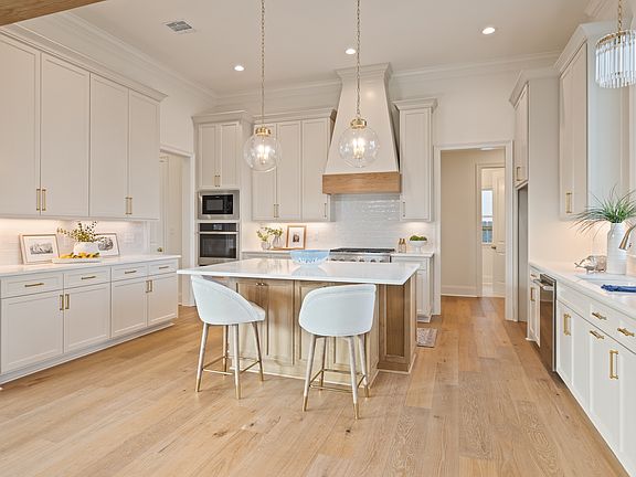 Kitchen island with white stools and wall ovens