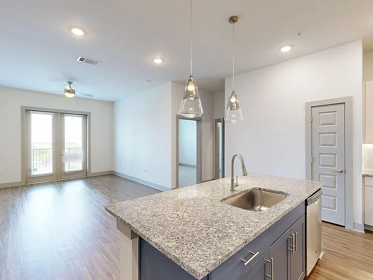 Apartment Kitchen with Stainless Steel Appliances, Dining and Living Room with Wood-Style Flooring.