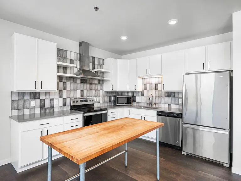 Modern kitchen with sleek stainless steel appliances, white cabinetry, and a stylish wooden island. Modern kitchen with sleek stainless steel appliances, white cabinetry, and a stylish wooden island.