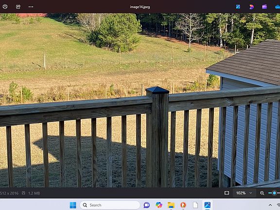 View of large back yard and storage building with adjoining farm.