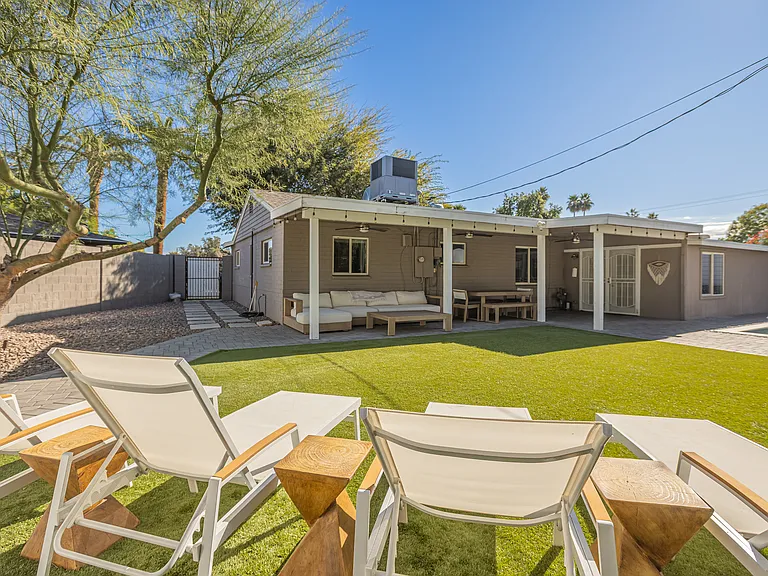 Sun loungers overlooking the expansive backyard, sparkling pool and covered patio
