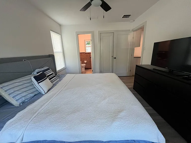 King - Primary bedroom with attached bathroom. USB/Lightning charging ports on the bed. A dresser and a 42" TV.