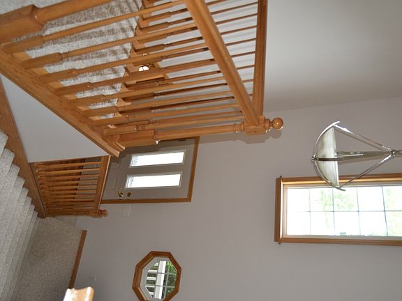 The front entry is two stories.  It features a couple unique windows and a nice chandelier.  The open staircase is trimmed out in Oak to match the wood floors.