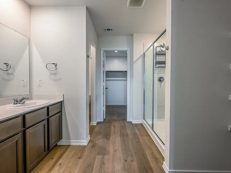 Large, primary bathroom with ample counter space, cabinets and linen shelving and walk in closet.