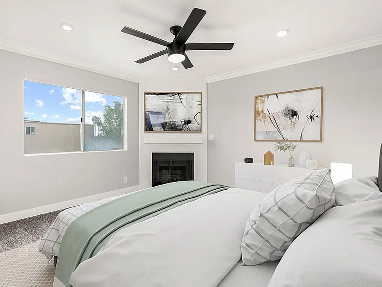 Carpeted bedroom with ceiling fan and private fireplace.