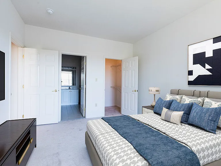 Primary bedroom with primary bath and walk in closet plus large windows with blinds.