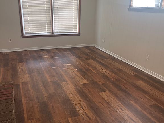 Large den with vinyl flooring. House has a den and a living room with dining room attached.