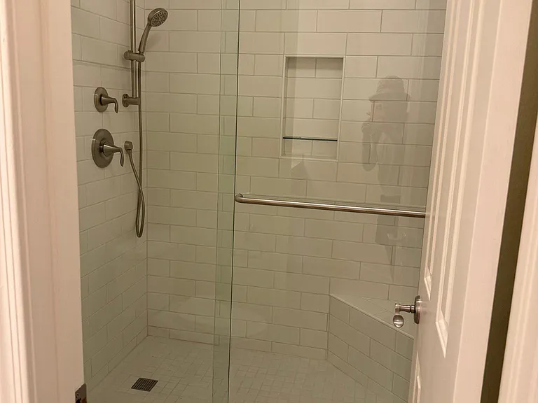 New shower has sliding glass barn door, a corner seat, and nook for shampoo and soap. New fixtures, including hose sprayer.