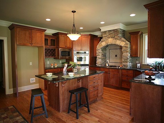 Designer kitchen has stone arch over the cooktop and stainless appliances.