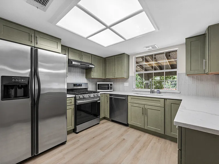 Newly renovated kitchen with gorgeous quartz countertops and sage green cabinets. The stove, dishwasher, and fixtures are all new and premium quality.