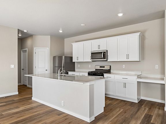 The kitchen has stainless steel appliances and plank flooring.