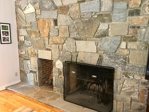 Den rock wall fireplace with nook for firewood.