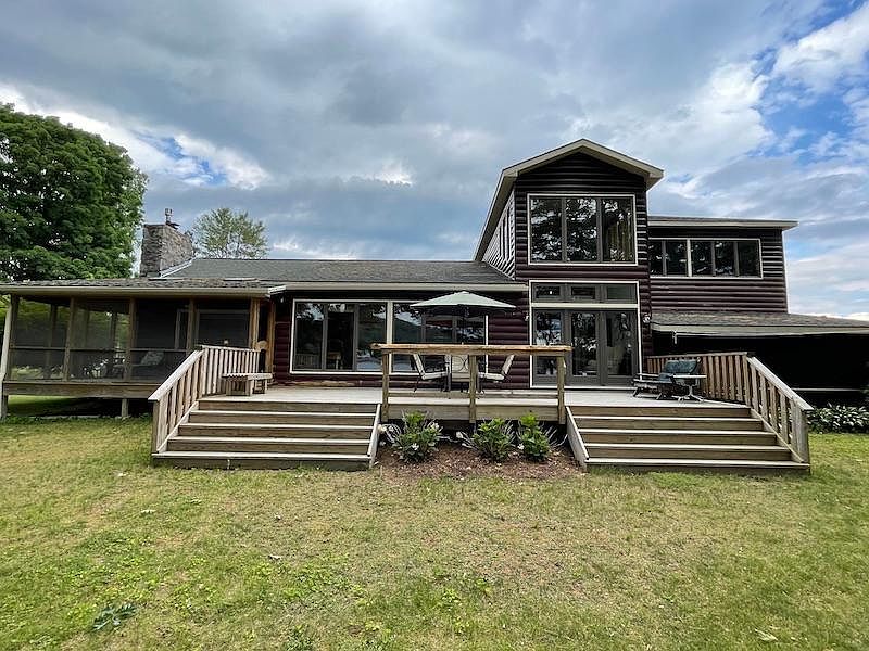Just look at these incredible windows overlooking the lake! 
You can see the super large deck with patio table and chairs. To the left side, you can see the screened in room that also has another table and chairs for eating outdoors.