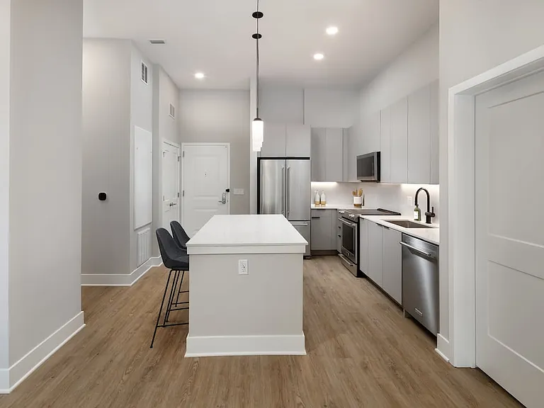 Signature Collection kitchen with stainless steel appliances, light grey cabinetry, marbled quartz countertops and backsplash, under-cabinet lighting, and hard surface flooring