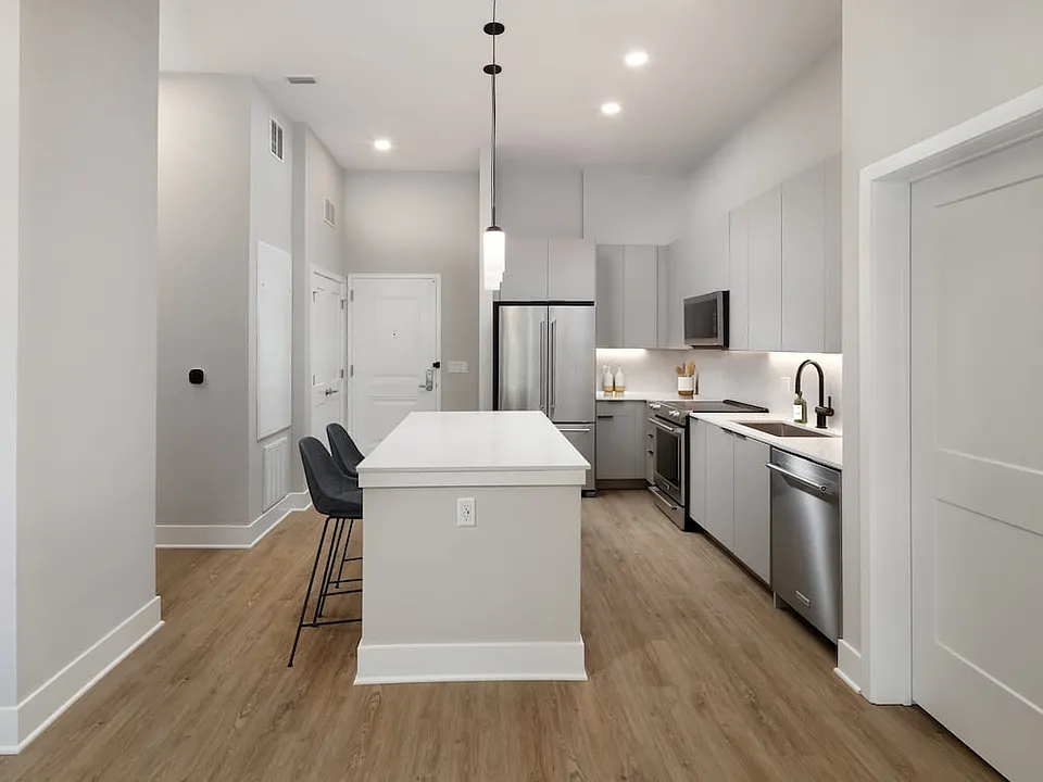 Signature Collection kitchen with stainless steel appliances, light grey cabinetry, marbled quartz countertops and backsplash, under-cabinet lighting, and hard surface flooring