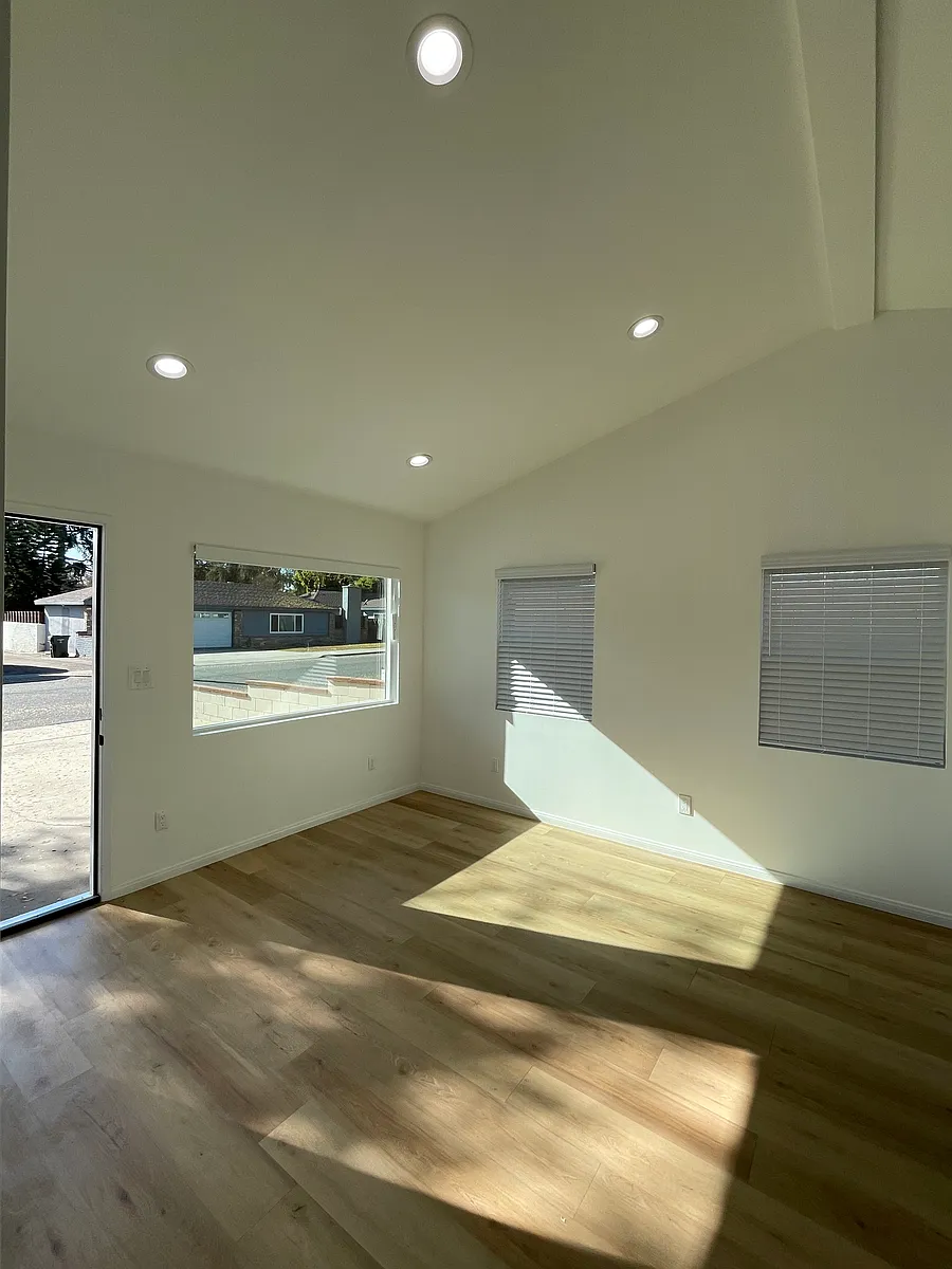 Sun-filled living space with high ceilings, multiple windows, and open layout. - 327 W Aliso St