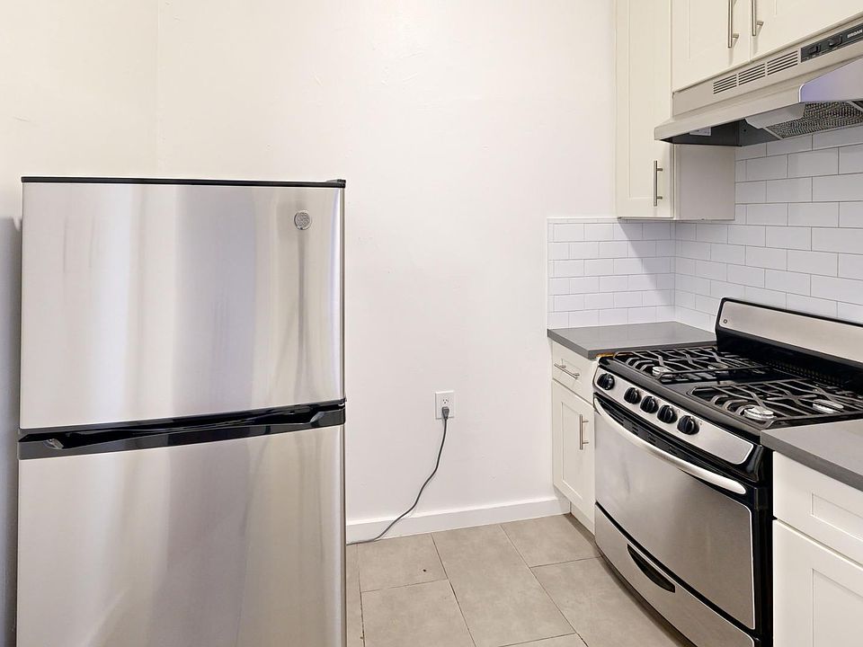 Kitchen with multiple cabinets, refrigerator, stove, range hood, and sink