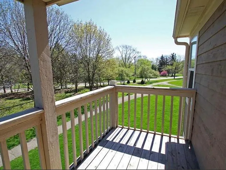 Sliding glass double doors lead to a private balcony overlooking a beautiful lake, open green space, and walking paths.