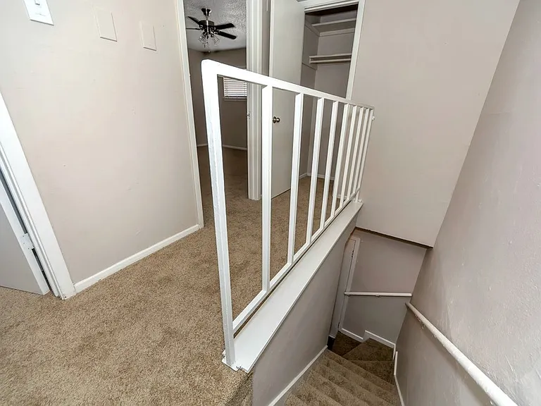 Townhome-style interior with carpeted staircase, upstairs landing, and convenient bedroom access at Watersong Villas Apartments.