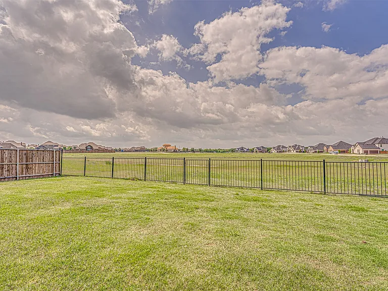 Expansive green lawn with a black metal fence enclosing the property