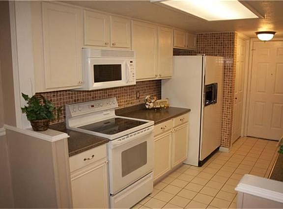 Left side of kitchen, glass top stove, microwave, side by side frig with icemaker, pantry with light