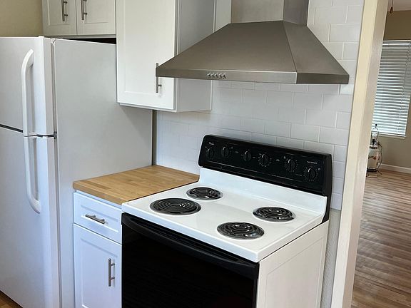 Stainless Range hood with stove and refrigerator.