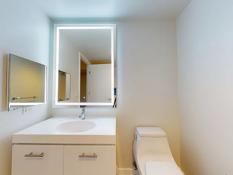 Apartment bathroom with LED vanity mirror.