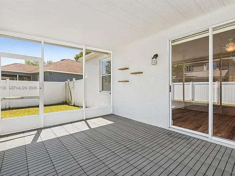 Covered screened patio offers a shaded outdoor area with tiled flooring and easy access through sliding glass doors.