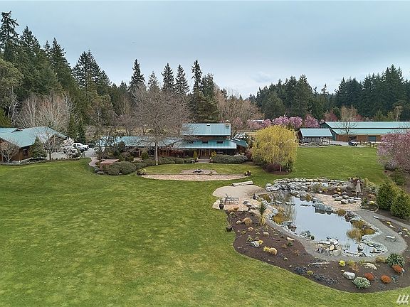 Beautiful yard with main house in the center foreground, 2 story guest suite and four car garage on left side of the photo, indoor tennis arena (could be converted back into a riding arena) on right side of photo and RV carport  with its own septic to the right of the main house.  Not seen is the other guest house which sits to the right of the arena as well as the riding pastures.