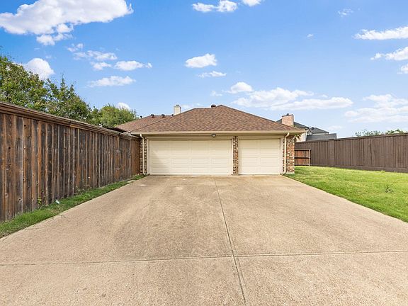 Spacious driveway leads to a detached two-car garage with fenced yard space for added privacy and storage.