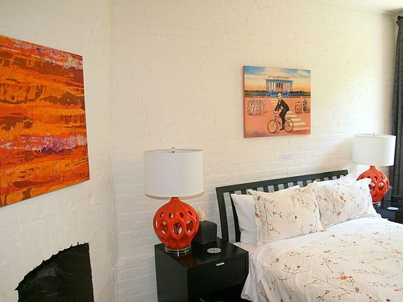 FRONT BEDROOM: hardwood floor, exposed brick wall, fireplace, and two south facing windows.