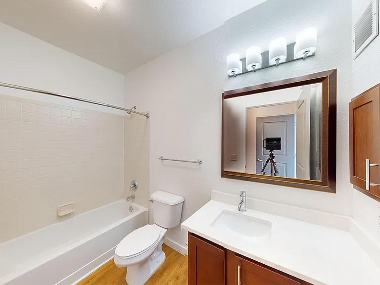 Apartment bathroom with wood-style flooring.
