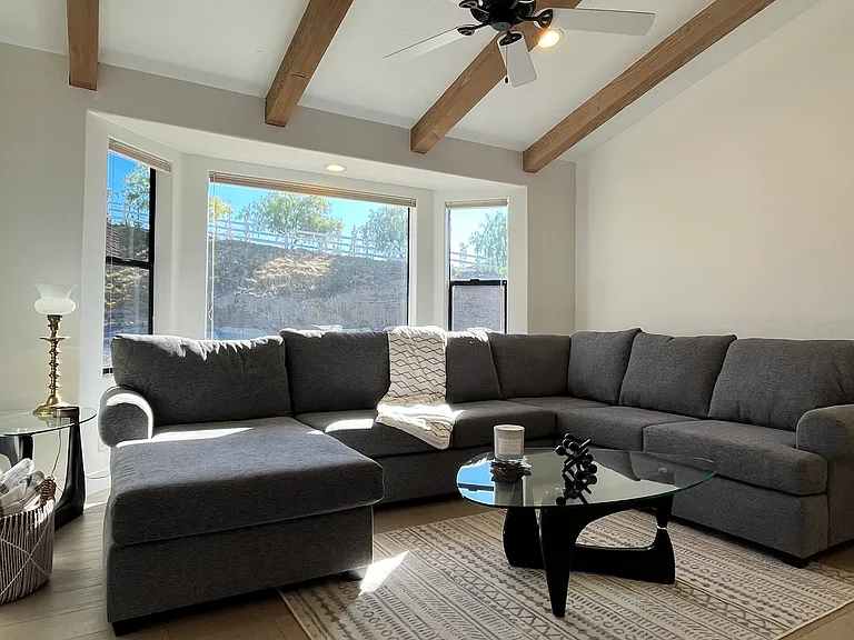 To the left of the front door is a spacious, sunken living space with natural wood beams