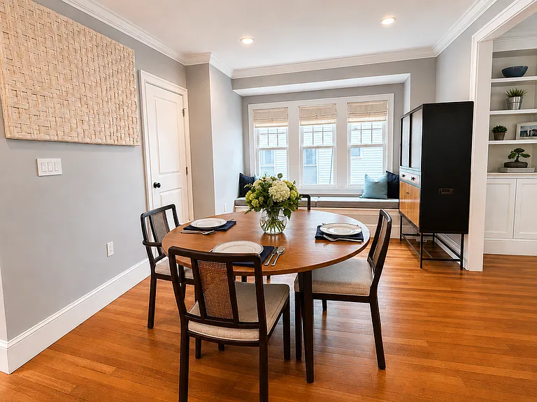 Elegant dining area with custom window bench seating and linen Roman shades