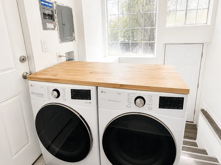 Shared laundry room with full-size washer and dryer and folding countertop.