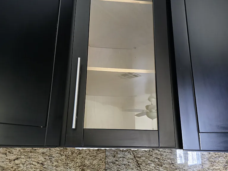 Two glass facing cabinets, kitchen has wood cabinets