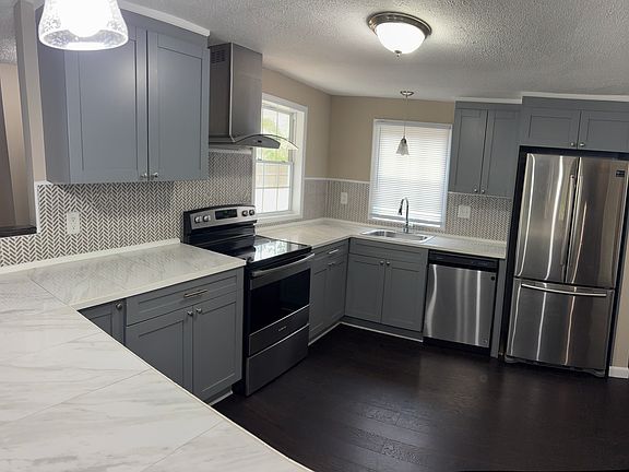 newer appliances, solid surface countertops, tiled back splash, modern vent hood.