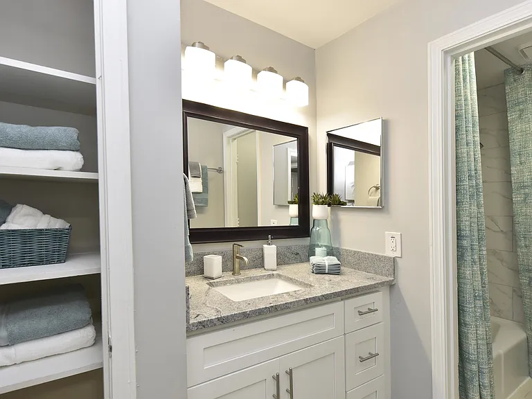 Bright bathroom with granite counters and linen closet