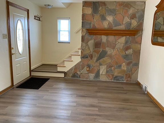 Stone accent wall with an oak mantle adds charm to the bright & cheerful living room.