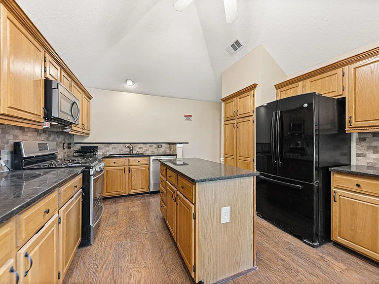 Spacious eat-in kitchen with ample wood cabinetry, center island, and full appliance suite for everyday cooking.