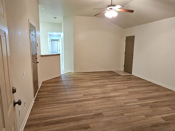 Spacious living room with white tile floors, vaulted ceilings, arched front window, and a back door that opens to a huge backyard_bright, open, and perfect for relaxing or entertaining.